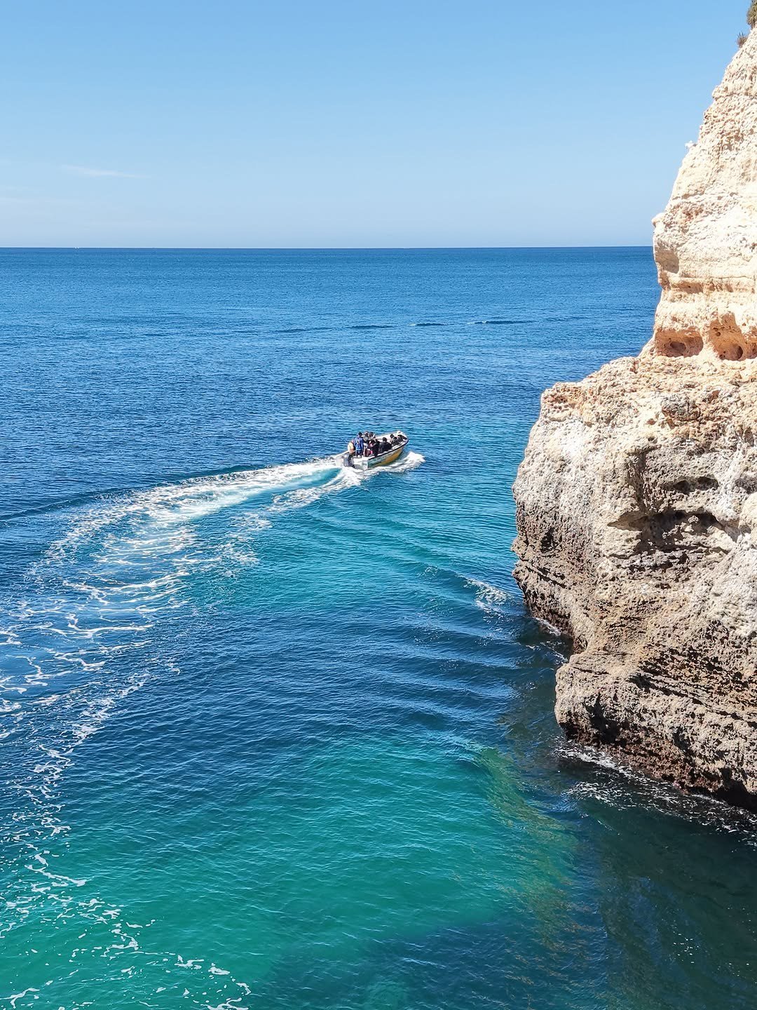 Mar azul-turquesa junto às falésias de Benagil, com um barco a passar